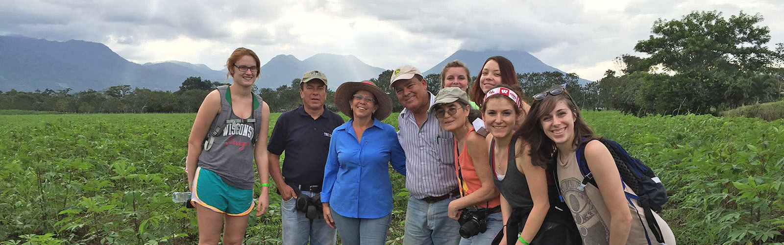 Students are together in a field. They are looking at the camera and smiling.